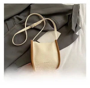 Detail showing litchi grain leather texture and brown edge stitching on small bucket bag