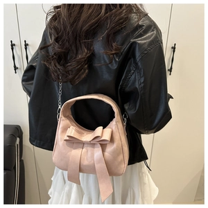 Detail showing pink bow shoulder bag with silver chain strap on a model's back
