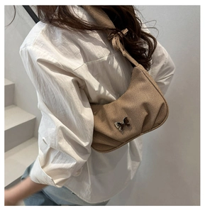 Brown corduroy shoulder bag featuring a stylish butterfly metal charm in a city setting