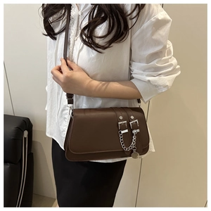 Close-up of a dark brown leather square bag featuring stylish double buckle straps