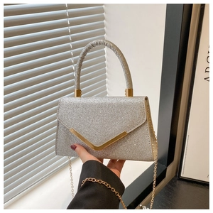 Close-up of silver sequin handbag with gold V-shaped metal buckle and luxury texture