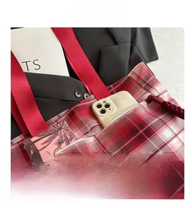 Detail view of red plaid tote bag with external pocket for phone and durable nylon handles