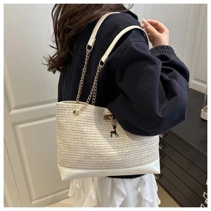 Straw woven tote bag with white leather base and deer charm shown on model's shoulder