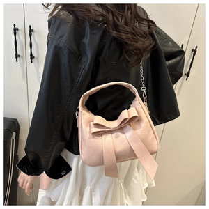 Detail of pink bow handbag showing matte leather texture and silver chain strap