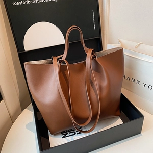 Minimalist brown oversized tote bag in faux leather for women, displayed in a luxury gift box