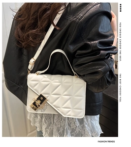 Detailed view of white quilted crossbody bag with gold chain and metal lock on a model