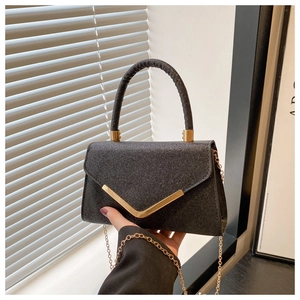 Detail of black glitter envelope handbag with V-shaped gold metal trim and chain strap
