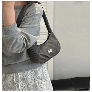 Detailed view of dark grey crescent shoulder bag featuring a silver butterfly buckle