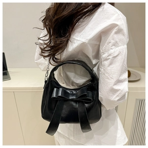 Rear view of black bow-knot handbag with silver chain strap worn by a model