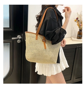 Détail d'un sac cabas en paille tissée avec anses en cuir marron et intérieur spacieux