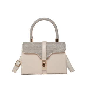 Elegant beige PU leather handbag with rhinestone handles and gold twist lock in frontal view