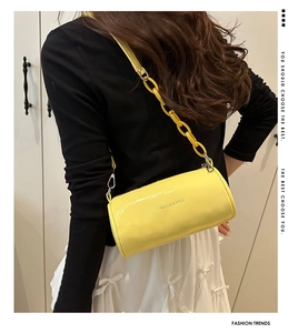 Dettaglio di una borsa a cilindro giallo brillante con tracolla a catena su modella
