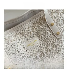 Detail of floral lace-style woven texture with leather logo tag on cream tote bag