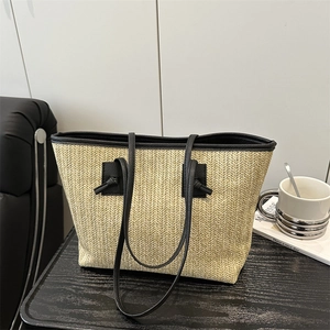 Straw tote bag with black leather straps and herringbone weave for summer beach vacations