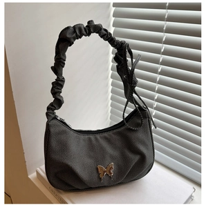 Detail of dark grey textured underarm bag featuring silver butterfly and scrunchie strap