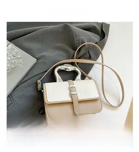 Detailed view of silver wave handle and beige leather texture on contrast square bag