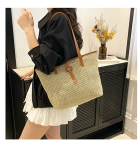 Détail du sac cabas en paille naturelle avec anses en cuir marron et boucle décorative