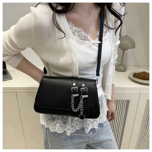 Detailed view of punk style black leather baguette bag with silver buckles and chain strap