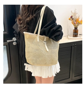 Vue détaillée d'un sac cabas en paille avec anses blanches dans une scène de vie