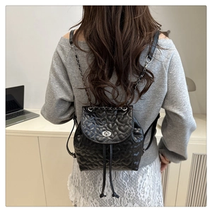 Rückansicht einer Frau mit schwarzem Rucksack mit Herzsteppung und Kettendetail