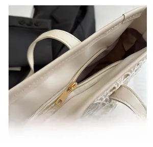 Detail of a woven tote bag showing smooth metal zipper closure and brown inner lining
