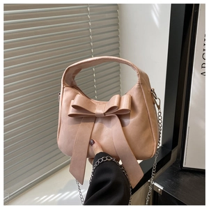 Close-up of light pink bow handbag with fine PU leather texture and silver chain strap