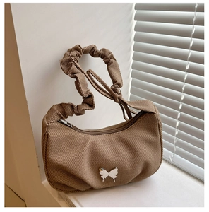 Detail of brown corduroy shoulder bag with silver butterfly emblem and pleated handle