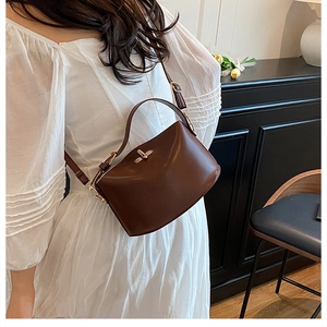 Moderne braune Leder-Umhängetasche mit Goldschloss in einer minimalistischen Umgebung