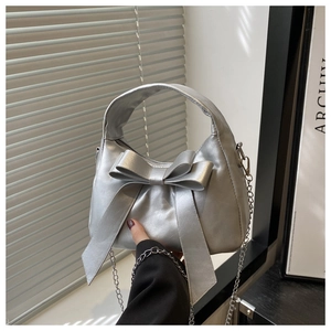Detail of silver metallic bow bag with sleek chain strap and elegant zipper closure