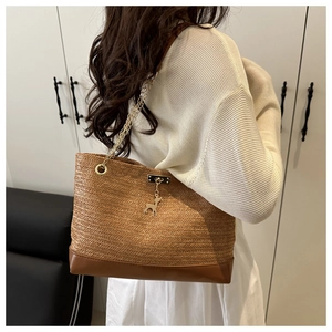 Détail du sac cabas en paille avec base en cuir et breloque cerf porté par un mannequin