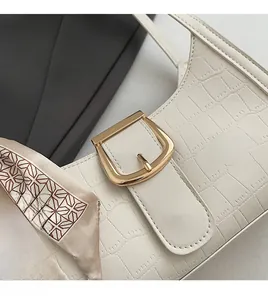 Gros plan d'un sac porté épaule blanc motif croco avec foulard et boucle dorée