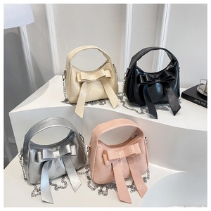 Detail of four colorful bow hobo bags with metallic chain straps in a group display