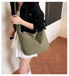 Olive green pleated nylon crossbody bag shown worn by a model for size and capacity detail