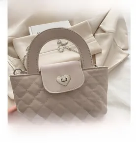 Detailansicht der cremefarbenen Stepptasche mit silbernem Herz-Drehverschluss und feiner Naht