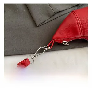 Details der roten Croissant-Tasche mit silbernem Karabinerverschluss und Metall-Zipper