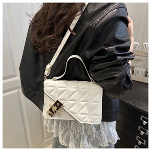 Close-up of white quilted handbag with golden lock and chain on model's shoulder