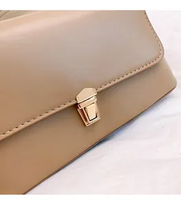 Détail macro du sac à bandoulière en cuir beige avec coutures nettes et boucle dorée