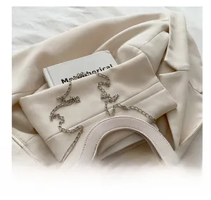 Detail der beigen Stepptasche mit silbernem Herz-Drehverschluss und Kettenriemen