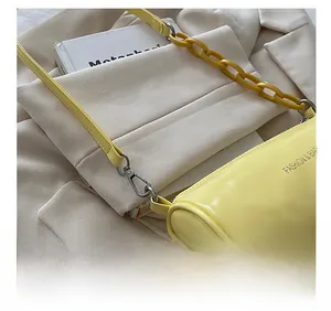 Détail d'un sac cylindrique jaune vif avec chaîne en plastique et cuir synthétique brillant