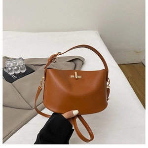 Close-up of caramel brown leather bucket bag with a golden cylindrical twist lock