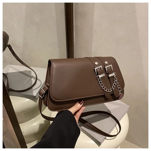 Detail of dark brown leather baguette bag featuring silver buckles and metallic chain
