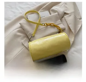 Détail du sac cylindrique jaune avec chaîne en résine et téléphone pour taille