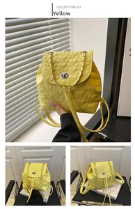 Detail eines gelben Rucksacks mit Herzsteppung, silbernem Drehverschluss und Kette
