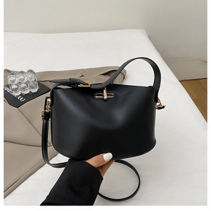 Detail of minimalist black matte leather bag with golden metallic twist-lock closure