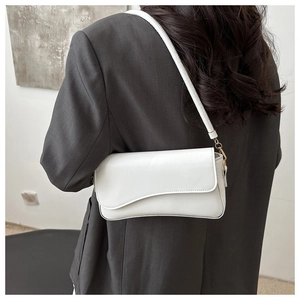 Detalle de bolso blanco de hombro con solapa ondulada y hebilla dorada en traje