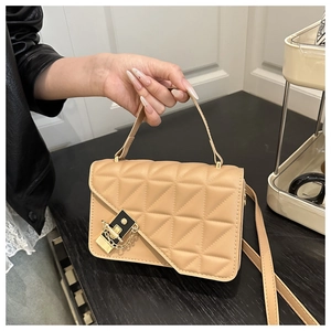 Detail of beige quilted handbag featuring gold metal clasp and chain link decoration