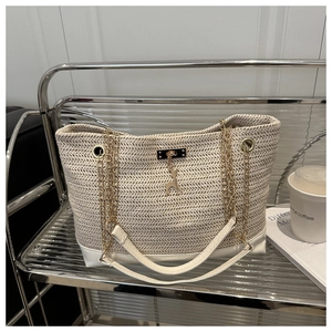 Detail of straw woven tote with golden elk pendant and white leather base on a shelf