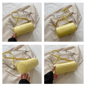 Détail du sac cylindrique jaune avec chaîne assortie et texture en cuir lisse et brillant