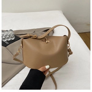 Close-up of stylish beige bucket bag featuring a gold twist lock and adjustable strap
