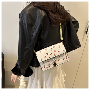 White leather crossbody bag with red cherry prints shown on model with shoulder strap